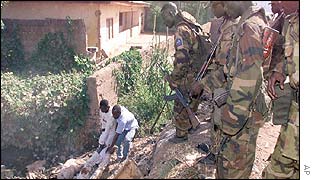 Soldiers watch people moving dead bodies