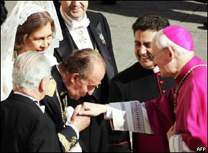 Spain's King Carlos kisses the hand of a US cardinal, while Queen Sofia looks on.