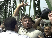 Iraqis celebrate after hanging the corpses on a bridge