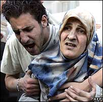 Man helping Tyre woman from her destroyed house