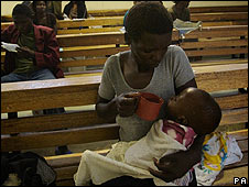 Woman feeds a child at the Budiriro Cholera clinic in Harare, Zimbabwe, in December 2008