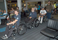 a queue of at least five men in manual chairs in an airport