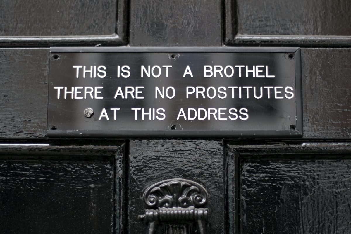 Sign saying "This is Not a Brothel. There Are No Prostitutes Here." from a street in Soho, London