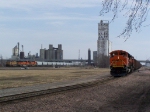 BNSF 9144 Waits While a UP Grain Train Makes its Way To the UP/BNSF Diamond With 2 Shiny New BNSF Swoosh Motors