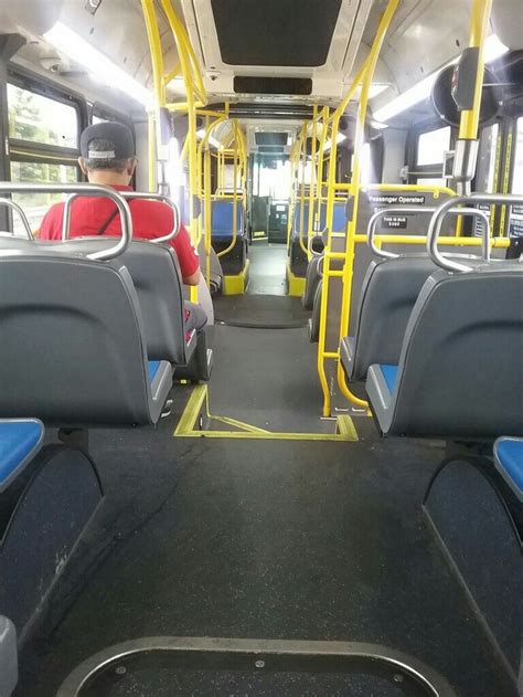 the inside of a bus with blue seats and yellow railings