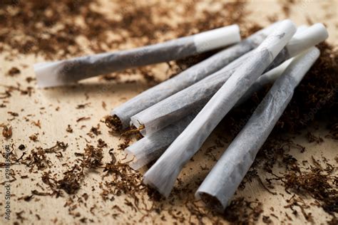 Hand rolling tobacco on a wood table Stock Photo | Adobe Stock