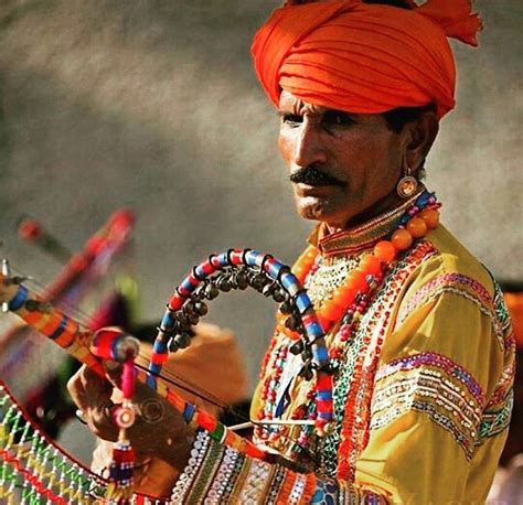 a man in an orange turban is holding a bow and wearing colorful bracelets