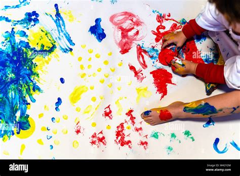 Toddler baby finger painting on a white paper on the floor Stock Photo ...