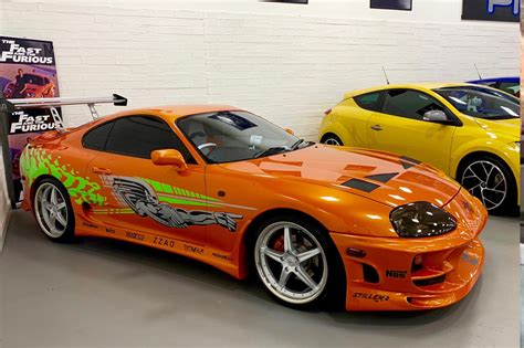 an orange sports car parked in a garage next to another yellow sport ...