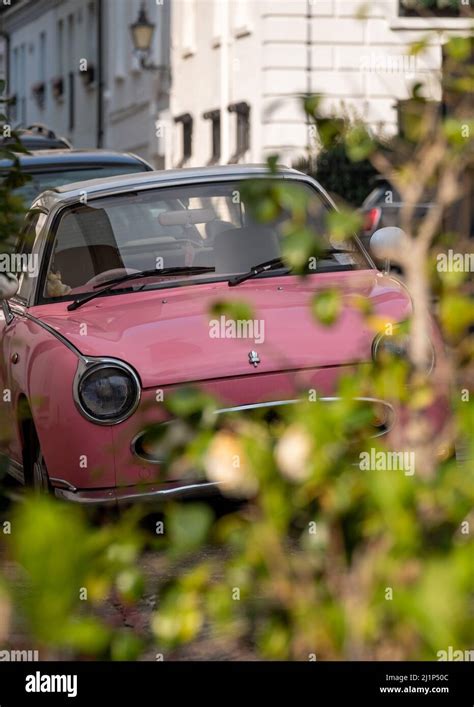 Cute pink Nissan Figaro retro style car, parked in a mews street in ...