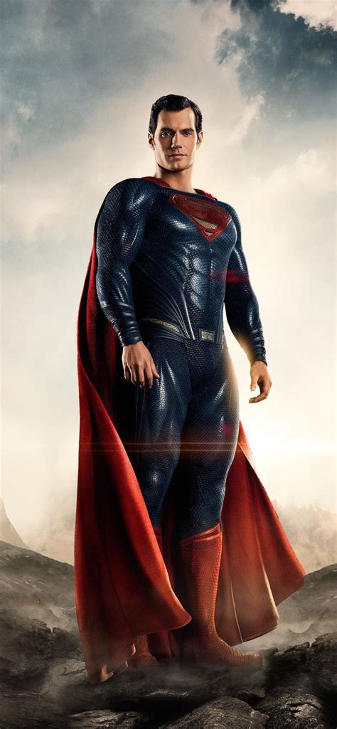 a man in a superman costume standing on top of a hill with his cape open