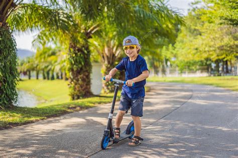 Premium Photo | Child on kick scooter in park kids learn to skate ...