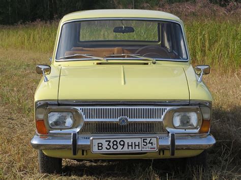 an old yellow car is parked in the grass