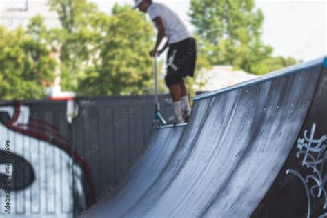 Skate park view with kids on a kick scooter doing tricks and stunts ...