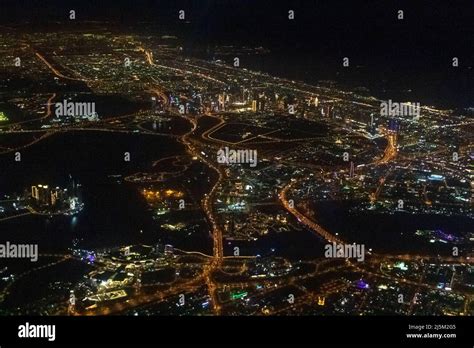 Night view of Dubai Skyline seen from flying plane above Persian Gulf ...