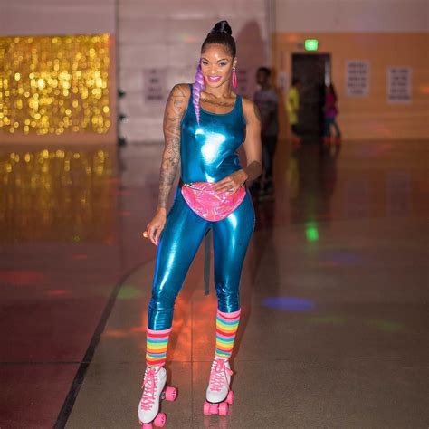 a woman in blue and neon pink roller skates posing for the camera with ...