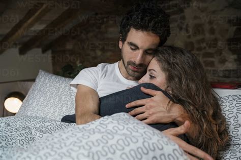 Romantic couple lying in bed hugging stock photo