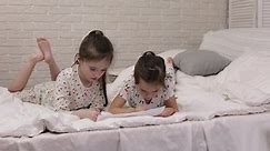 kids drawing pictures while lying on bed. pajama party and friendship.