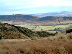 The view from Steel Rigg, onHadrian's Wall, to Barcombe Hill above Vindolanda. The fort lies just right of the picture, adjacent to the wood below the hill. In the far distance the Pennines continue.