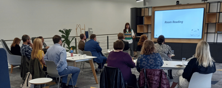 A group of business people in a seminar with a lecturer at the front with a screen