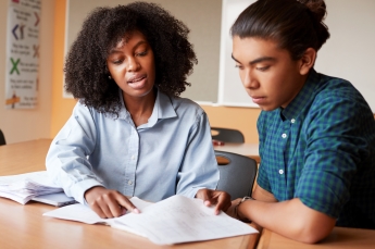 A teacher and a student review some papers